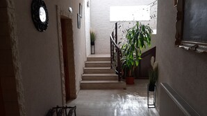 Un pasillo con una escalera, una planta en maceta y un radiador.