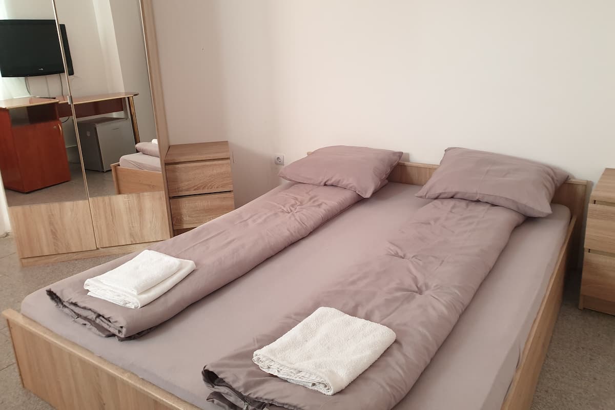 Ein Einzelbett mit Holzrahmen, zwei Kissen und zwei gefaltete Handtücher.