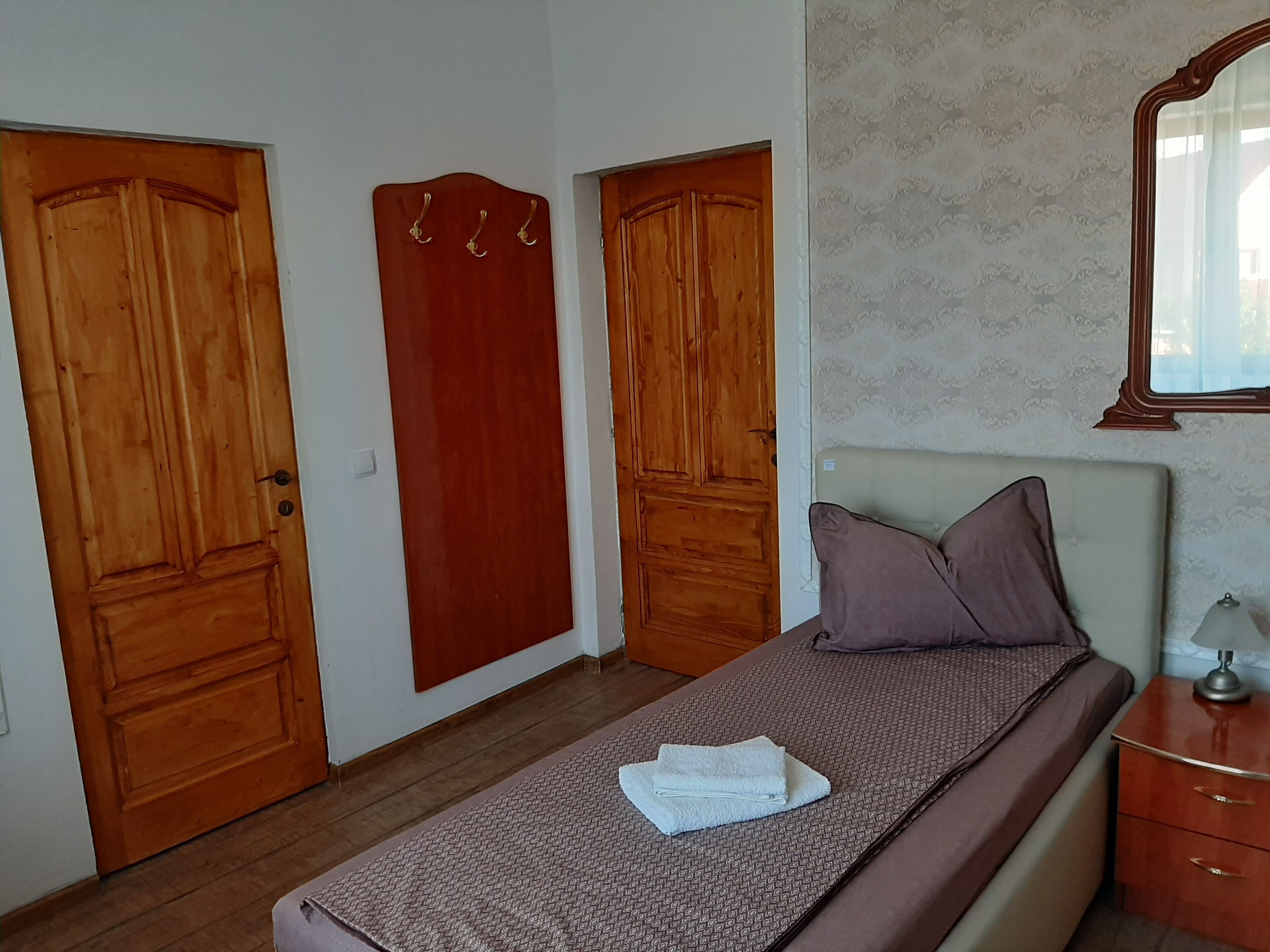 A bedroom with a bed, a nightstand, and two wooden doors.