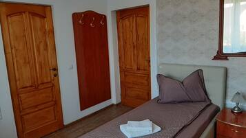 A bedroom with a bed, a nightstand, and two wooden doors.