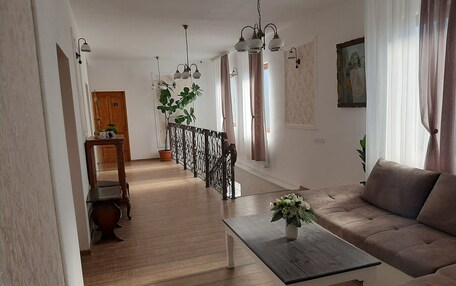 A spacious living area with a wooden floor, a sofa, a coffee table, and a staircase leading to another room.