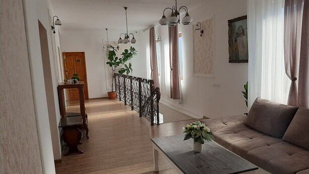 Amplia sala de estar con piso de madera, un sofá, una mesita de centro y una escalera que lleva a otra habitación.