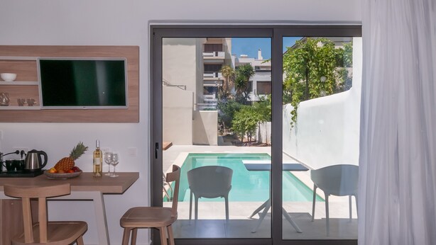 Una habitación moderna con vista a la piscina, un comedor con sillas y una mesa, y un televisor montado en la pared.