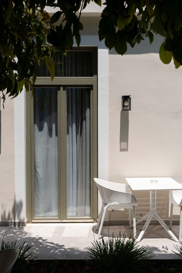 A modern outdoor seating area with a white table and chairs, a sliding glass door, and a small wall-mounted light fixture.