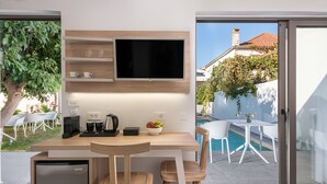 Una cocina moderna con televisión integrada, armarios de madera y un refrigerador pequeño.