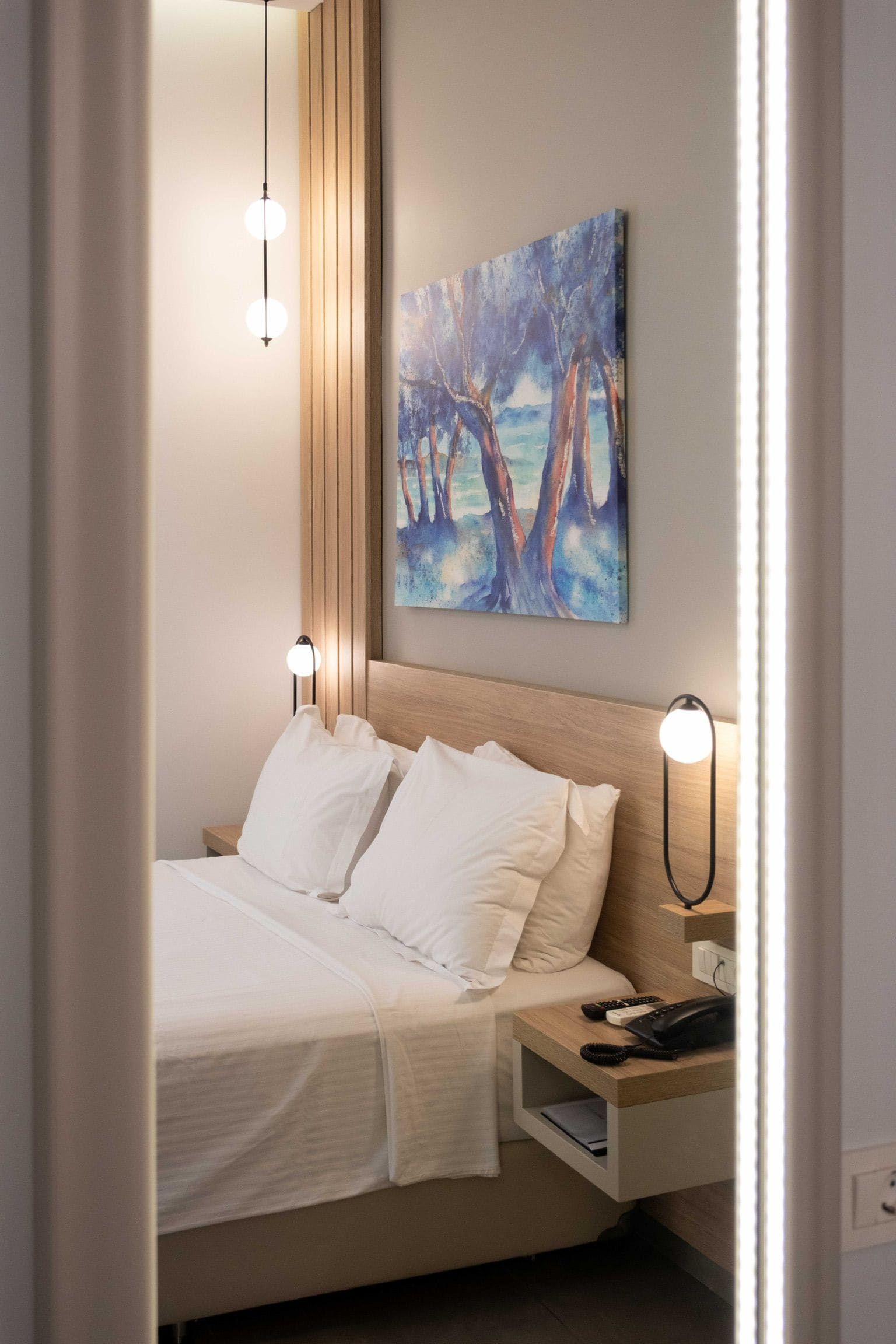 A neatly made bed with white linens, a headboard, and bedside lamps.