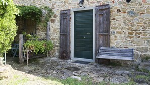 A stone building with a green door, wooden shutters, a bench, and a wheelbarrow. - "The fireplace"discover the Tuscan peculiarities getting lost in landscapes (Vicchio)