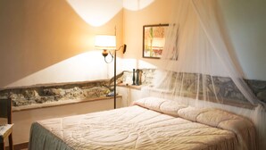 A bedroom with a large bed, a nightstand, a lamp, and a window with a view of the outside. - "The fireplace"discover the Tuscan peculiarities getting lost in landscapes (Vicchio)