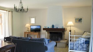 Una sala de estar con sofá, televisor, chimenea y comedor con mesa y sillas.