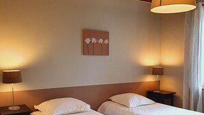 Una habitación de hotel con dos camas individuales, techo de madera y un cuadro de flores colgado en la pared.