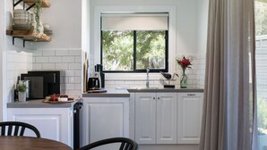 A modern kitchen with white cabinets, a built-in oven, and a window with a view of greenery.