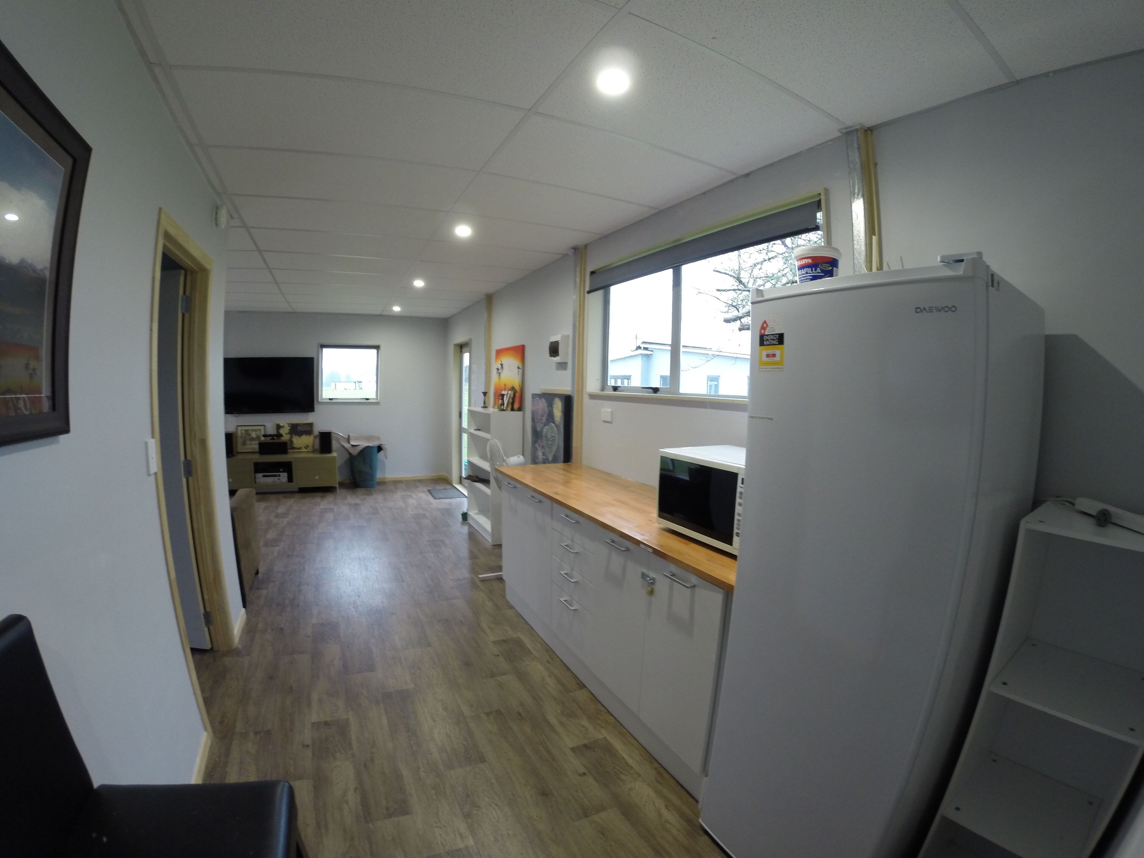 A modern kitchen with a refrigerator, microwave, and wooden countertop.