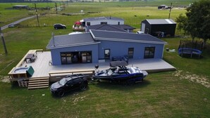A modern house with a large deck, a boat, and a car parked in the driveway. - Full holiday home to yourself, up to 21 guests (Atiamuri)