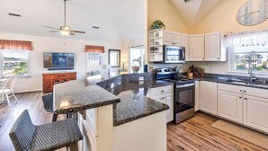 A kitchen with granite countertops, white cabinets, a built-in oven, and a large window with a view. - Sea the Day | 717 ft from the beach | Private Pool, Hot Tub | Nags Head (Nags Head)