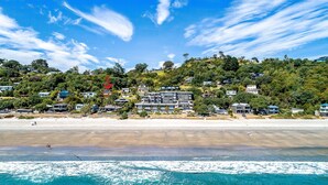 A coastal residential area with beachfront properties, clear skies, and a view of the ocean. - SANDCASTLE ON ONETANGI | Be My Guest (Onetangi)