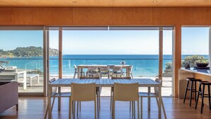 A spacious room with a large sliding glass door leading to a balcony overlooking the sea. - SANDCASTLE ON ONETANGI | Be My Guest (Onetangi)