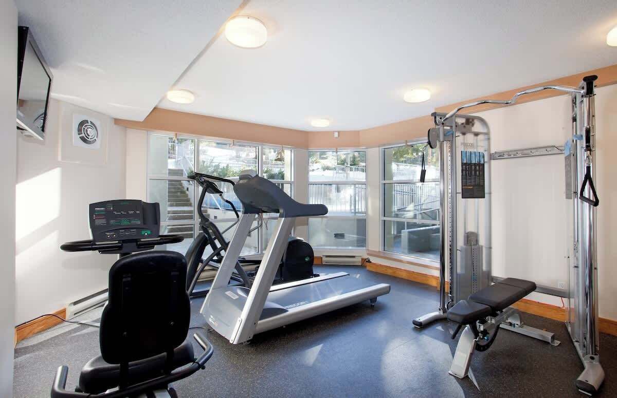 A gym with a treadmill, weight bench, and exercise equipment.