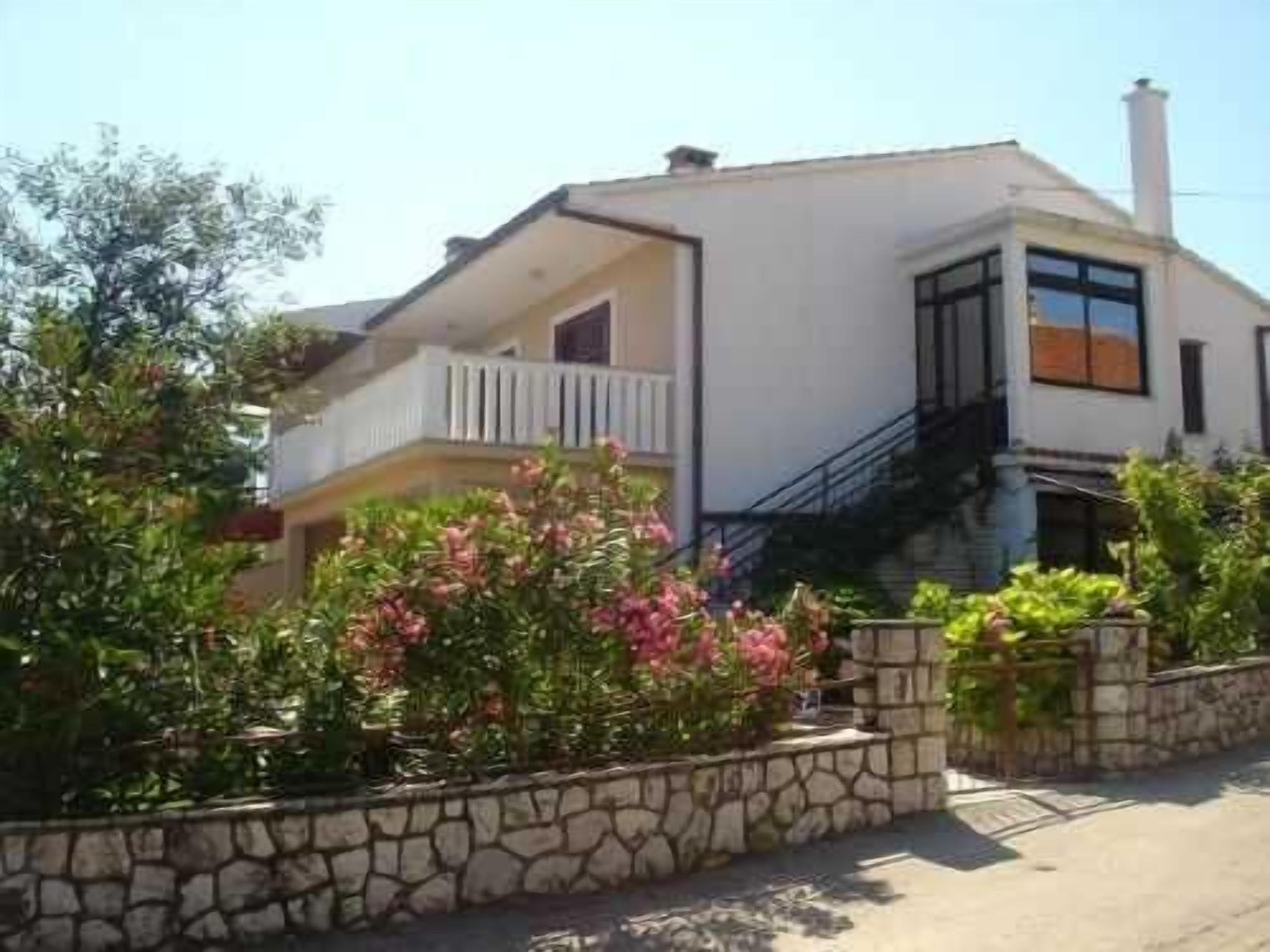 A two-story house with a balcony, a stone wall, and a staircase leading to the upper floor.