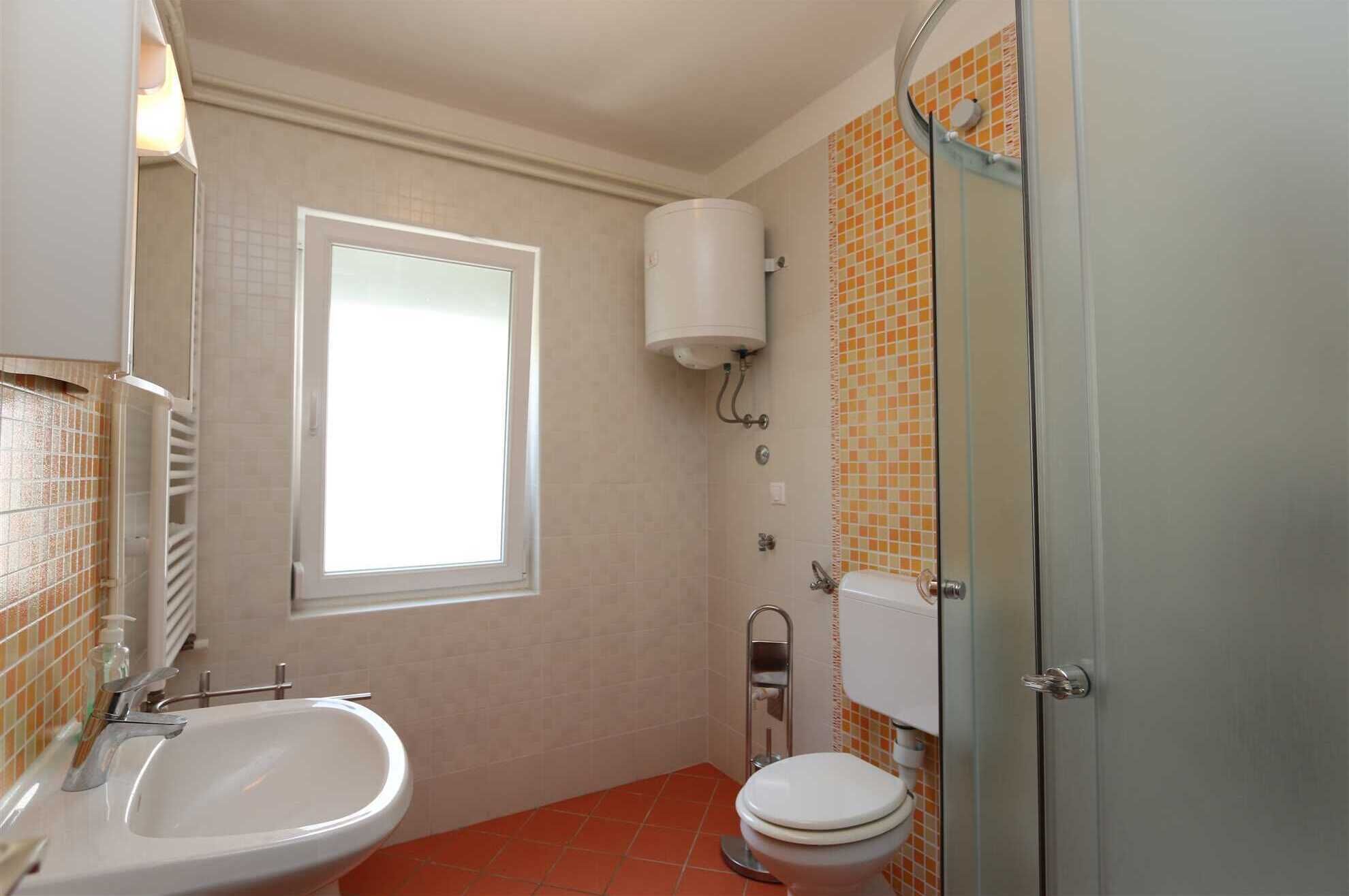 Et badeværelse med toilet, håndvask og bruser.