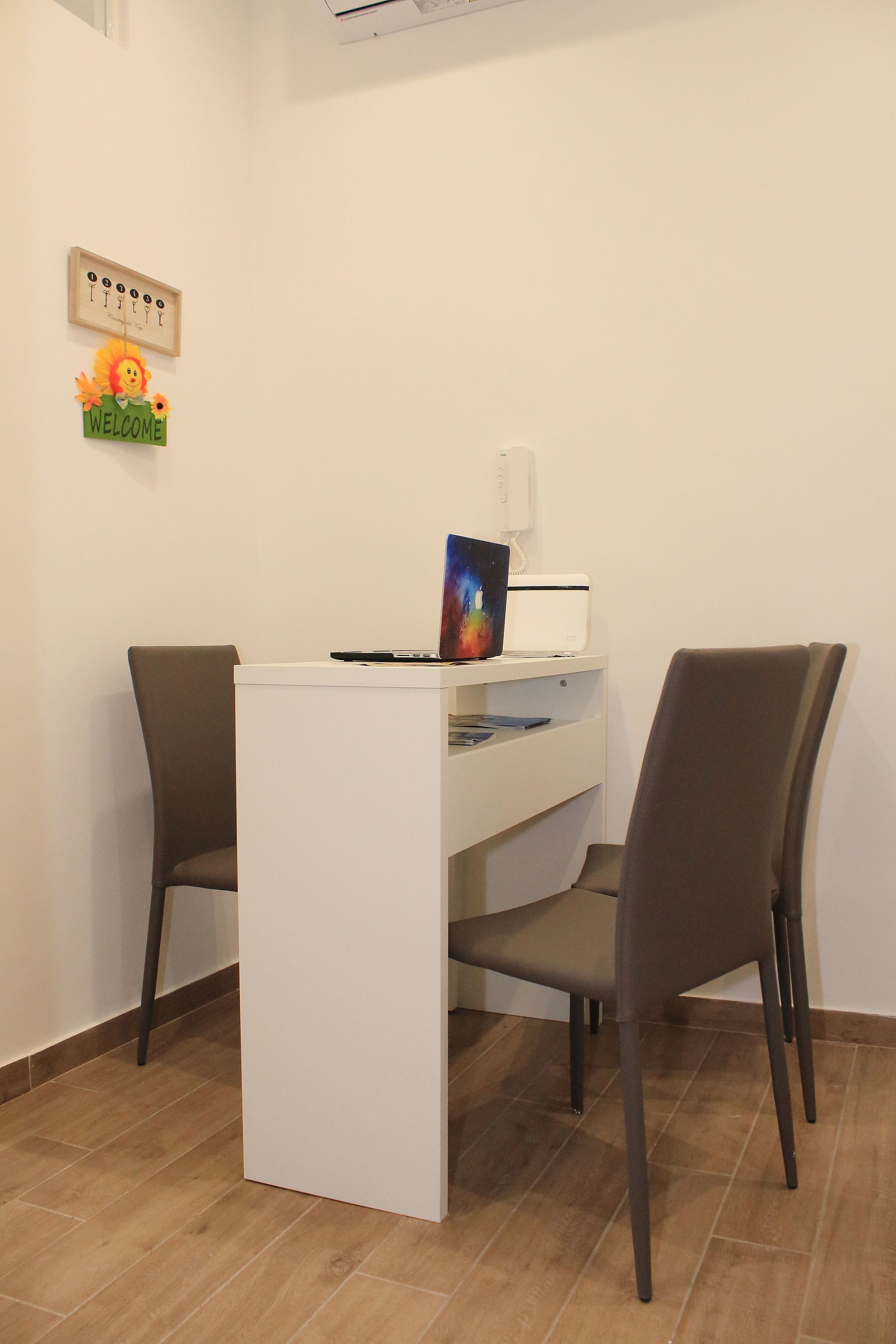 Una reception con due sedie, un portatile e un cartello di benvenuto.