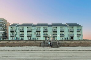 A multi-story hotel with a uniform exterior, located adjacent to a sandy beach.