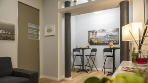 A modern living room with a sofa, a dining area with two chairs, a table with food, and a painting on the wall. - Vesù (Naples)