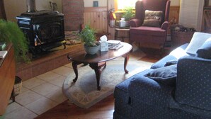 A cozy living room with a fireplace, a comfortable armchair, a sofa, and a coffee table. - Rustic Elegance to Feed Your Soul in the Heart of Pennsylvania (Loganton)