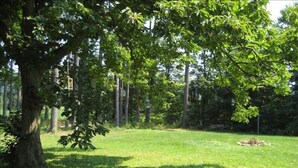 A grassy area with trees and a small pile of logs. - Rustic Elegance to Feed Your Soul in the Heart of Pennsylvania (Loganton)