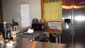 A kitchen with a stainless steel refrigerator, stove, and microwave. There are fruits on the counter and a kettle on the stove. - Rustic Elegance to Feed Your Soul in the Heart of Pennsylvania (Loganton)