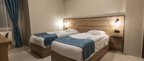 A bedroom with two beds, wooden headboards, and bedside lamps.