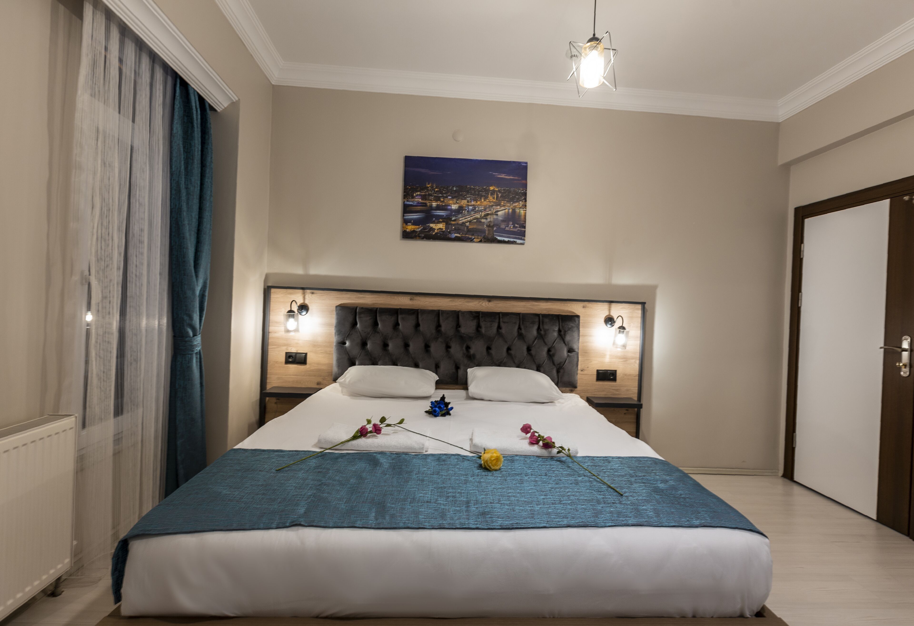 Un lit bien fait, avec une couverture bleue, deux oreillers et des fleurs décoratives.