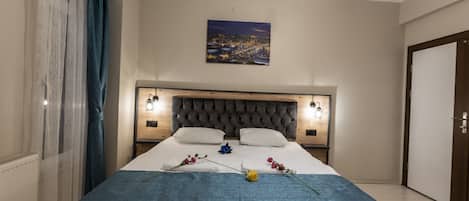 A neatly made bed with a blue blanket, two pillows, and decorative flowers.