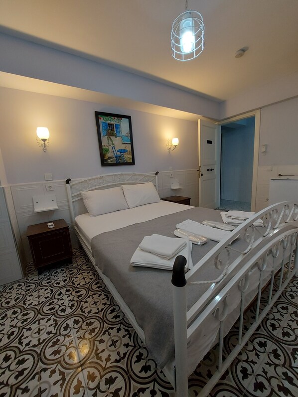 Un dormitorio ordenado con cama, mesitas de noche, un cuadro y una puerta.