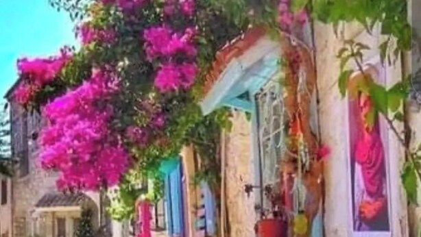 A traditional building with a courtyard, a small seating area, and vibrant bougainvillea flowers. - Alada Garden Otel (Bozcaada)