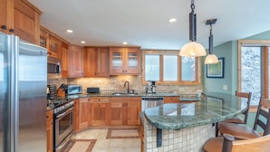 A modern kitchen with wooden cabinets, stainless steel appliances, and a granite island. - Beautiful 3 bedroom Condo close to Lift 7 (Telluride)