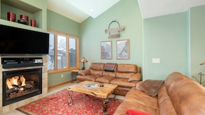 A living room with a fireplace, leather sofa, and a television. - Beautiful 3 bedroom Condo close to Lift 7 (Telluride)
