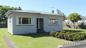 A single-story house with a front porch, a satellite dish, and a small front yard with a picket fence. - right in the town centre (Whakatane)
