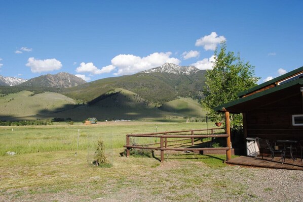 Una cabaña rústica con terraza de madera y vistas a una cadena montañosa.