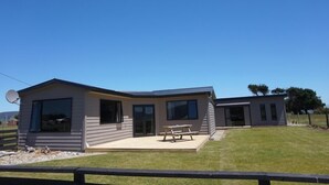 Een modern gelijkvloers huis met plat dak, grote ramen en een overdekt terras.