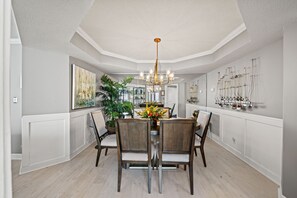 A dining area with a chandelier, wooden chairs, and a table with a centerpiece. - Great Ocean View and recently updated + Free Attraction Tickets! (Myrtle Beach)