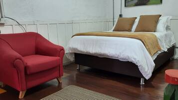 Un dormitorio con cama, un sillón rojo y un radiador.