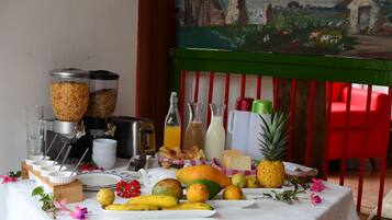 A breakfast table with various fruits, beverages, and breakfast items.