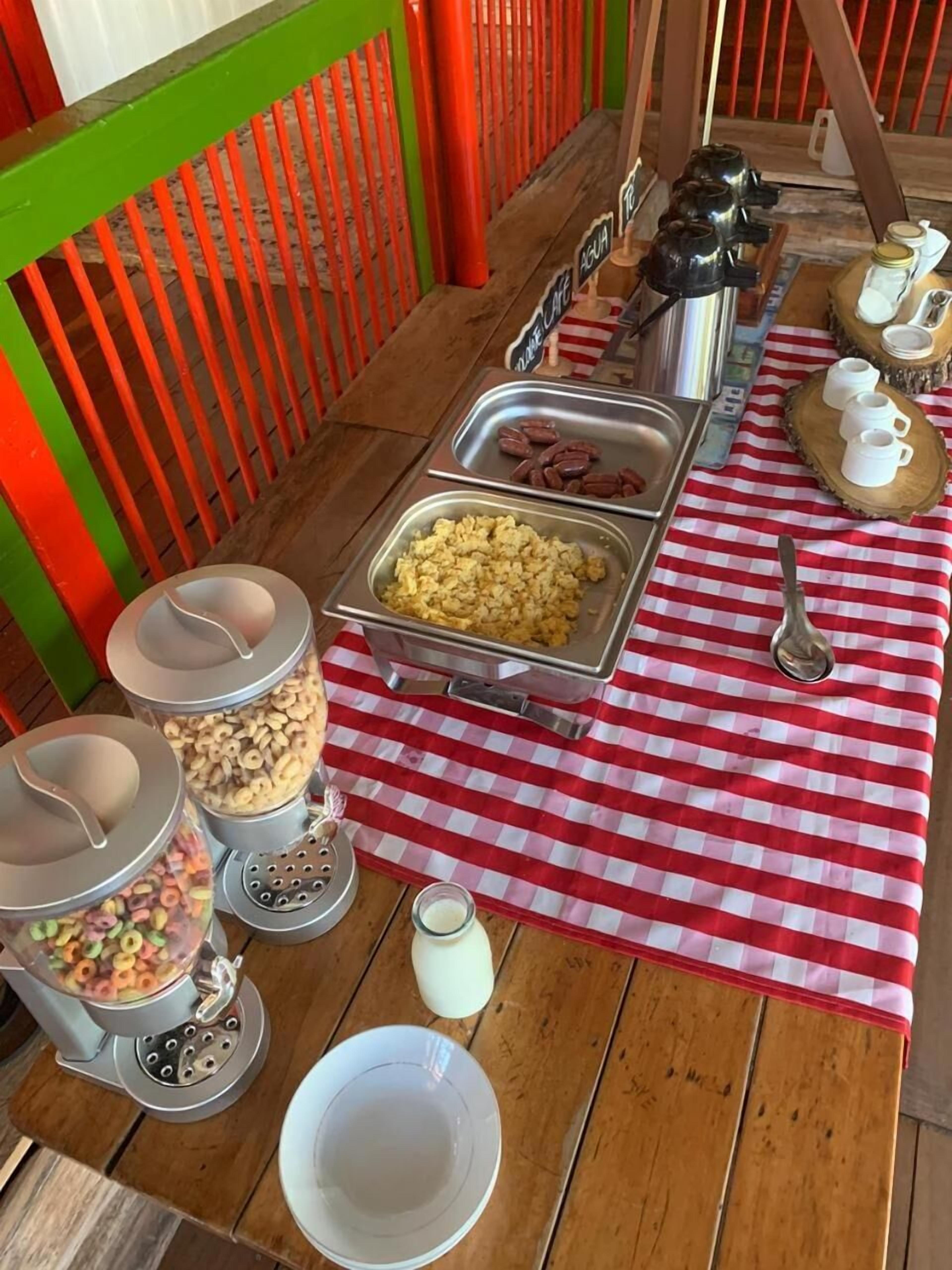 Un bufé de desayuno con diversas opciones de comida y utensilios sobre un mantel a cuadros.