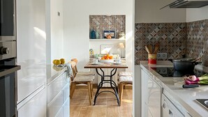 Een moderne keuken met witte kasten, een houten eettafel en een decoratieve spatwand.