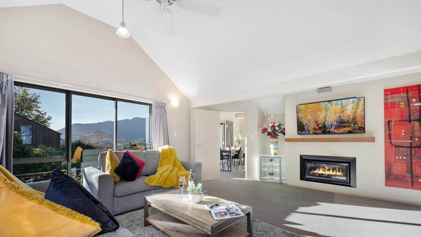 A modern living room with a grey sofa, a wooden coffee table, and a fireplace. - LARGE DISTINCTIVE AND SPACIOUS FAMILY HOME (Queenstown)