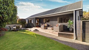 A modern house with a covered patio, outdoor seating, and a well-maintained garden. - LARGE DISTINCTIVE AND SPACIOUS FAMILY HOME (Queenstown)
