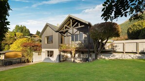 A modern two-story house with a sloped roof, large windows, and a visible air conditioning unit. - LARGE DISTINCTIVE AND SPACIOUS FAMILY HOME (Queenstown)