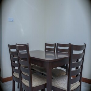A round wooden dining table with six chairs, each with a cushioned seat. - Nemadek Le Royal (Mombasa)