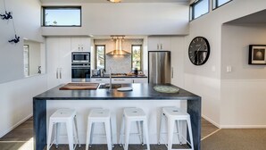 Une cuisine moderne dotée d’un îlot central, d’appareils électroménagers en acier inoxydable et d’une grande fenêtre.