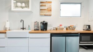 A modern kitchen with white cabinets, a dishwasher, a coffee maker, and a microwave. - Visit Sports and Culture Venues from an Artful Garden Studio in Central Phoenix (Phoenix)